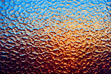 Nahaufnahme eines durchleuchteten Strukturglas, oder Ornamentglas mit orangenem und blauen...