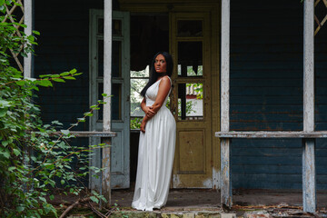 black young African woman in a white dress in front of an abandoned house destroyed by a hurricane - Powered by Adobe