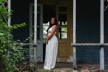 black young African woman in a white dress in front of an abandoned house destroyed by a hurricane