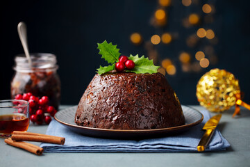Christmas pudding, fruit cake. Traditional festive dessert. Dark background with lights garland....