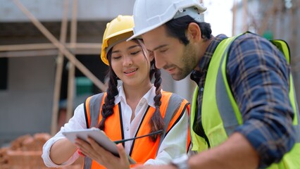 Young female assistant engineer holding tablet on hands opening plan details to Caucasian male...