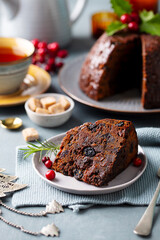 Christmas pudding, fruit cake with cup of tea. Traditional festive dessert. Grey background. Close up.