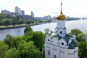 Buildings and skyscrapers in city Dnipro, Ukraine. Beautiful white christian Orthodox church near...