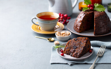 Christmas pudding, fruit cake with cup of tea. Traditional festive dessert. Grey background. Copy space.