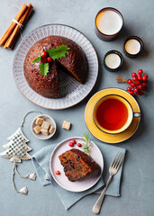 Christmas pudding, fruit cake with cup of tea. Traditional festive dessert. Grey background. Top view.