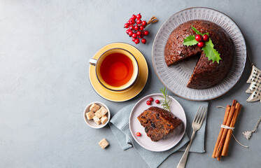 Christmas pudding, fruit cake with cup of tea. Traditional festive dessert. Grey background. Copy...
