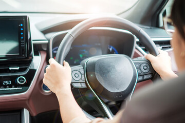 woman driver driving a car on the road, hand controlling steering wheel in electric modern automobile. Journey, trip and safety Transportation concepts