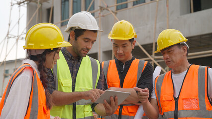 Group of professional multicultural engineers specialists using tablet to open project plan...