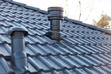Ventilation pipe and chimney on the roof of a new house
