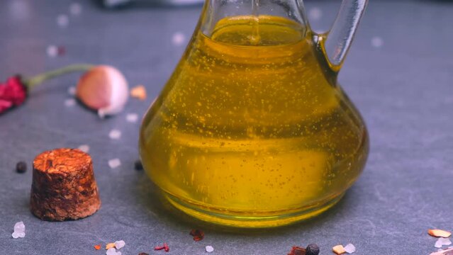 vegetable oil, olive, sunflower, rapeseed or unrefined almond is poured into a transparent bottle on a dark background.