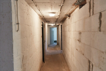 Fototapeta premium Narrow corridor in the basement with light