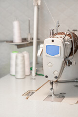 Sewing machine close-up on the background of coils with white threads