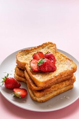 Traditional french toasts with strawberries and honey on pink background. Summer breakfast, brunch or lunch with berries. Copy space. Selective focus.