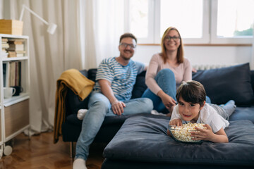 family at home, watching television and eating popcorn
