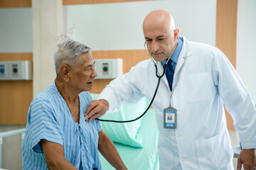 European male doctor uses a stethoscope to examine the heart lungs of an elderly man with heart disease. A medical professional advises and talks to psychotherapy for hospital patients.