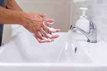 Person hands wash with soap bubbles and rinse with clean water to prevent and stop the spread of...