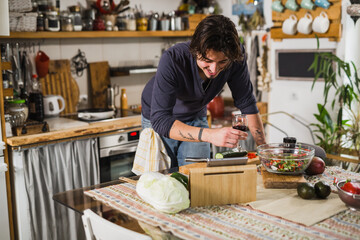 man looking on digital tablet while preparing food in kitchen