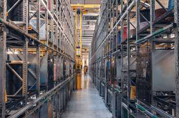 Interior of a modern storage warehouse with coils of colored cable on metal shelves. Forklift lift...
