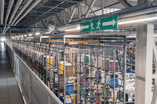 Colored cable wound on spools. Metal shelves with colored spools of cable at the factory. Side view.