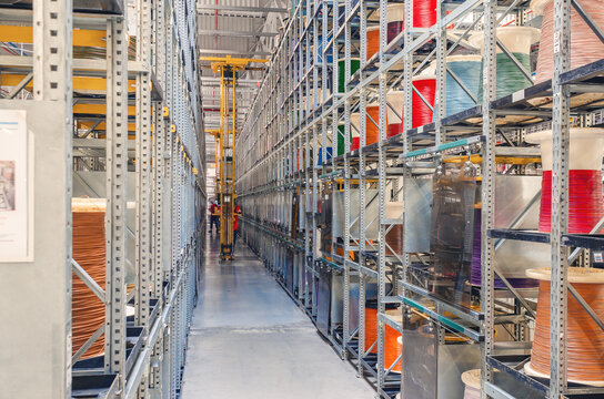 Interior of a modern storage warehouse with coils of colored cable on metal shelves. Forklift lift at the factory.