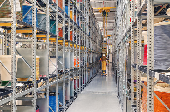 Interior of a modern storage warehouse with coils of colored cable on metal shelves. Forklift at the factory.