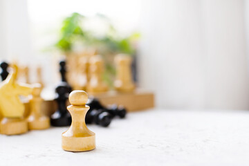 International Chess Day. Beautiful wooden chess stands on a white table against the background of...