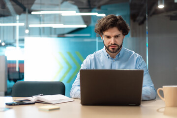 Business man using laptop sitting on chair in modern office