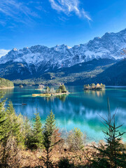 Lake Eibsee, Germany in autumn times with snow-covered mountains in the background and green forest...