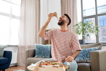 food delivery, consumption and people concept - happy man eating takeaway pizza at home