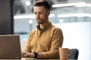 Male Office Worker Working On Laptop Sitting At Workplace Indoor