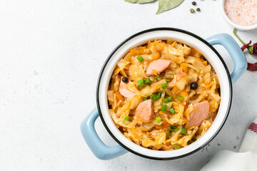 Slow cooker cabbage stew with sausages  in a pot. Top view, copy space.