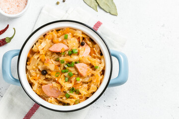 Slow cooker cabbage stew with sausages  in a pot. Top view, copy space.