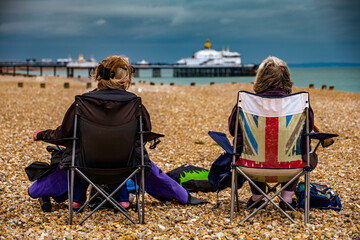 pair of anon persons sitting on beach with union jack chair