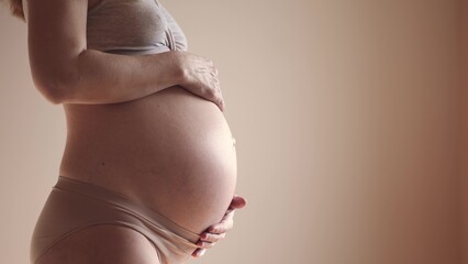 pregnant woman. health sunlight pregnancy motherhood procreation concept. close-up belly of a pregnant woman. woman waiting for a newborn baby. pregnant woman holding her belly indoors - obrazy, fototapety, plakaty
