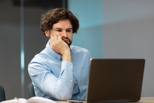 Bired business man leaning head on hand using pc