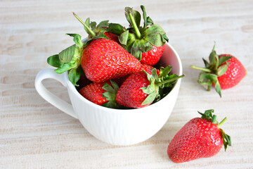 fresh garden strawberry in white cup on pastel background, close-up