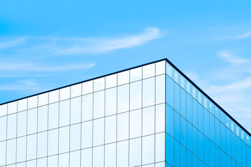 Low angle view of glass skyscraper with sunlight reflection on surface against blue sky background