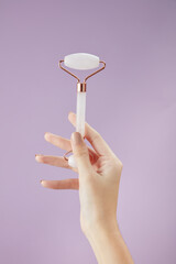 Top view of holding cosmetic roller on hand in purple background for cosmetic advertising