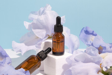 Serum with floral extracts for skincare. Nature cosmetics in glass bottles with pipette and iris...