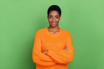 Photo of nice millennial brunette guy crossed arms wear orange pullover isolated on green color...