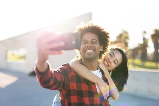 Beautiful young couple in love walking at the city street. Happy couple taking selfie photo
