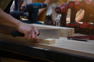 Carpenter working and sawing on wood craft at workshop to produce wooden furniture.