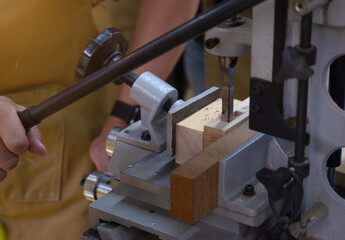 Close up. Carpenter working with drilling machine in carpentry workshop. 