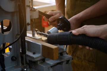 Carpenter working with a drill press to make hole on the work bench. 