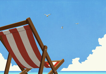 Seagulls flying in summer blue sky over striped beach chair
