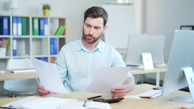 Difficult for a male employee to deal with paperwork. documents. Stressed caucasian businessman confused by mistake, looking through papers. bookkeeper, booker vaguely, dimly sitting at work in office