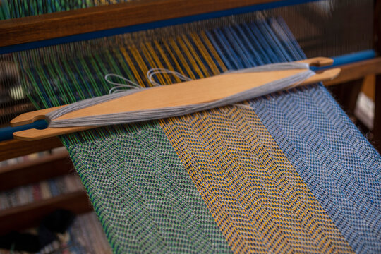 Blue, green and orange thread forming pattern on loom
