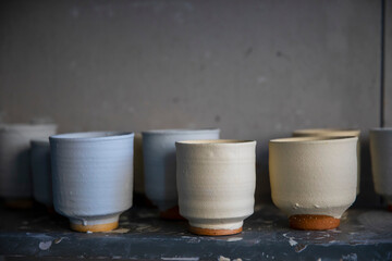 Clay pottery cups drying on shelf
