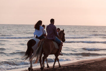 The family spends time with their children while riding horses together on a sandy beach. Selective...