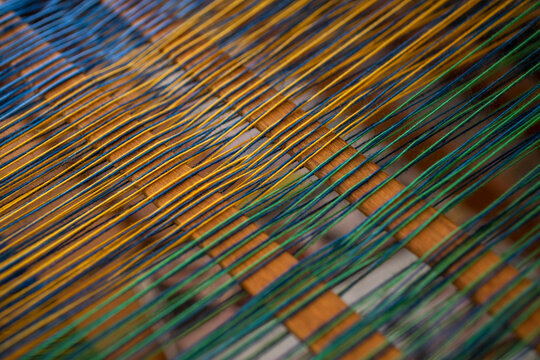 Close up green and yellow thread on loom
